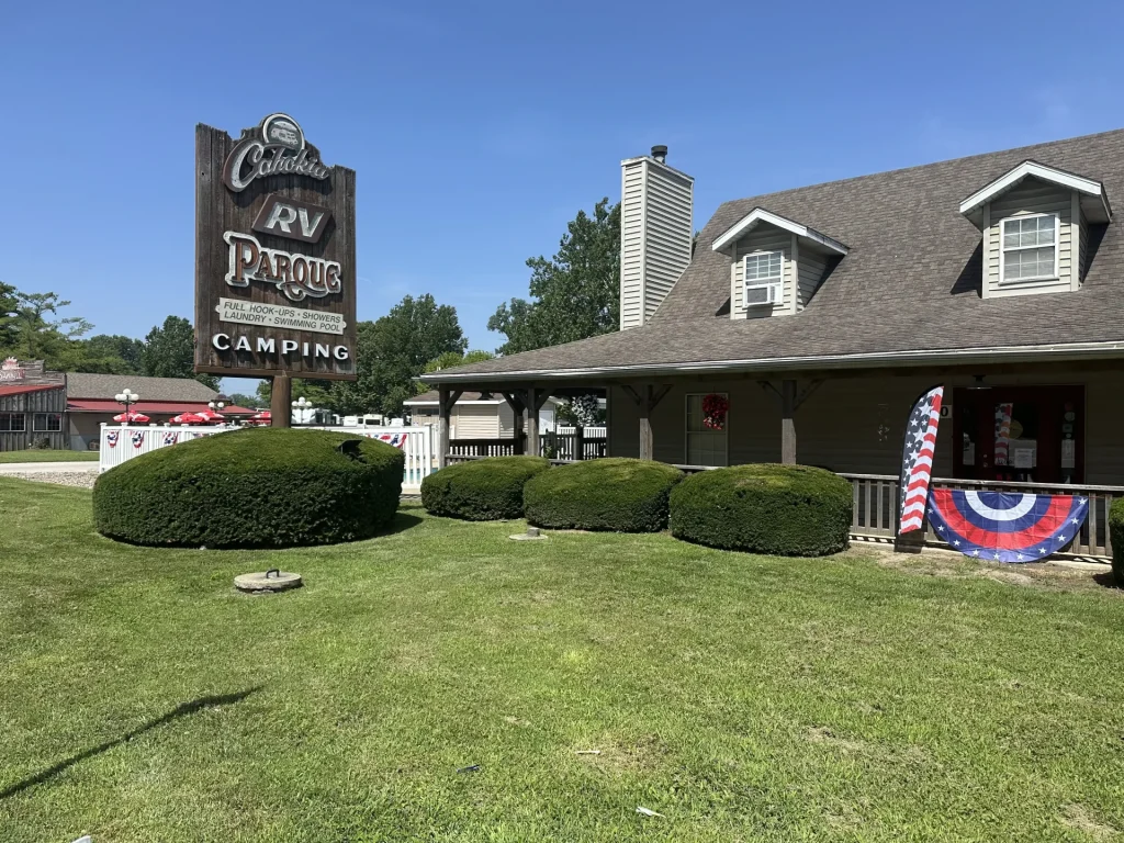 Cahokia RV Parque wooden entrance sign listing full hookups, showers, laundry, and swimming pool